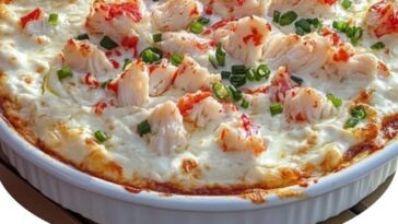 Creamy crab dip in a skillet, topped with melted cheese and served with toasted bread slices.