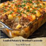 Baked casserole with layers of seasoned meatloaf, creamy mashed potatoes, melted cheese, and crispy bacon bits on top.