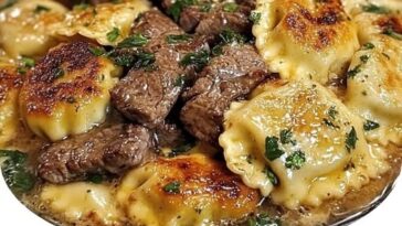 sizzling skillet filled with tender steak pieces and cheese ravioli in a rich garlic butter sauce, garnished with fresh herbs.