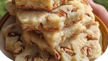 Pecan shortbread bars with a golden, buttery crust, topped with crunchy pecan pieces and a light dusting of powdered sugar.