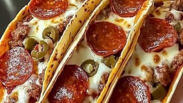 Close-up of pepperoni pizza tacos, with golden crispy taco shells filled with melted cheese, marinara sauce, and slices of pepperoni, garnished with fresh basil.