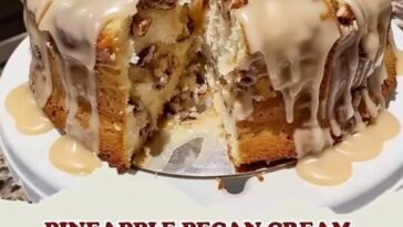 A moist pineapple pecan cream cheese pound cake, topped with a glaze and garnished with chopped pecans.