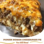 A slice of Pioneer Woman Cheeseburger Pie with a golden, flaky crust, filled with seasoned ground beef, melted cheese, and topped with lettuce and tomato.