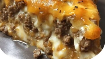 A slice of Pioneer Woman Cheeseburger Pie with a golden, flaky crust, filled with seasoned ground beef, melted cheese, and topped with lettuce and tomato.