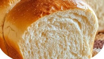 Freshly baked homemade bread loaf with a golden crust, sliced to reveal a soft, fluffy interior.