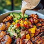 vibrant shrimp and avocado bowl topped with fresh mango salsa, creamy avocado slices, and a drizzle of lime-chili sauce, served in a bowl.