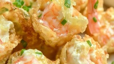 Crispy golden wontons filled with shrimp and cream cheese, arranged on a plate with a dipping sauce on the side.