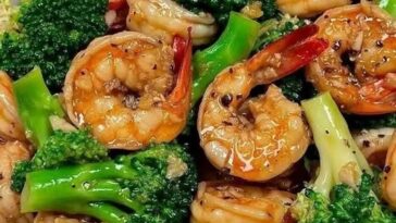 Stir-fried shrimp and broccoli with a savory sauce, served in a bowl with a garnish of sesame seeds and fresh green onions.