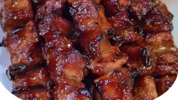 Grilled barbecue skewers with juicy meat and vegetables on a wooden board, garnished with herbs.