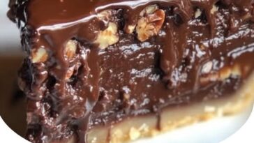 slice of Texas chocolate pecan pie with a glossy, rich filling of chocolate and pecans in a flaky, golden pie crust.