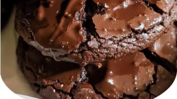 A plate of soft, chewy cookies topped with a rich chocolate frosting and chopped pecans.
