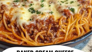A slice of baked cream cheese spaghetti casserole on a plate, with layers of creamy pasta, meat sauce, and melted cheese.