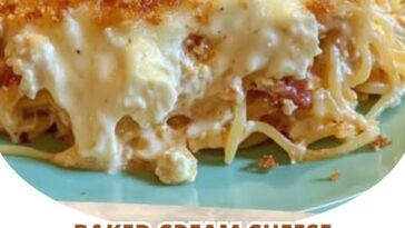 A serving of baked cream cheese spaghetti casserole, with melted cheese on top, rich tomato sauce, and creamy pasta layers.