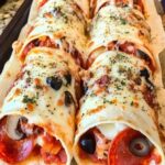 Golden-brown baked pizza wraps filled with cheese, pepperoni, and tomato sauce, served on a plate.