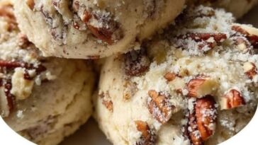 Freshly baked butter pecan cookies with golden brown edges and chopped pecans on top, arranged on a cooling rack.
