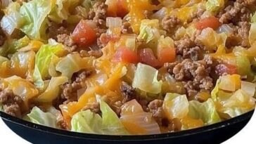 A hearty skillet filled with chopped cabbage, ground beef, rice, and tomato sauce, simmered together and garnished with fresh parsley.