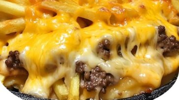 Baked casserole topped with golden French fries, melted cheese, and ground beef in a baking dish.