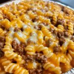 A skillet of cheesy sloppy cheeseburger pasta with ground beef, pasta shells, and melted cheese in a rich, savory sauce.