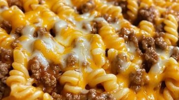A skillet of cheesy sloppy cheeseburger pasta with ground beef, pasta shells, and melted cheese in a rich, savory sauce.