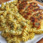 Creamy garlic Parmesan chicken served over cheesy twisted pasta with herbs.