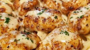 Creamy Parmesan pasta topped with sautéed garlic butter chicken, garnished with fresh herbs.