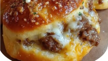 Golden-brown garlic parmesan cheeseburger bombs cut open to reveal melted cheese, seasoned ground beef, and soft dough.