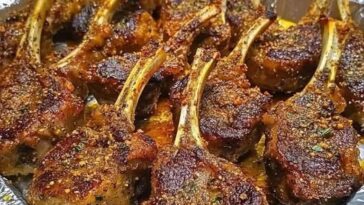 Crispy garlic parmesan fried lamb chops garnished with herbs and served on a white plate.