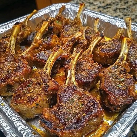 Crispy garlic parmesan fried lamb chops garnished with herbs and served on a white plate.