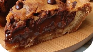 A slice of gooey Nutella-stuffed cookie pie with melted chocolate filling, served on a plate with a scoop of ice cream.