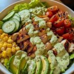 A fresh grilled chicken and avocado salad bowl with mixed greens, cherry tomatoes, and a light dressing.