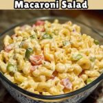 A bowl of creamy macaroni salad mixed with chopped jalapeños, crispy bacon, and a sprinkle of shredded cheddar cheese, topped with a dollop of sour cream.