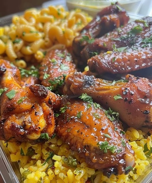 A plate featuring crispy lemon pepper chicken wings, fluffy yellow rice, and creamy macaroni and cheese, served as a hearty, comforting meal.