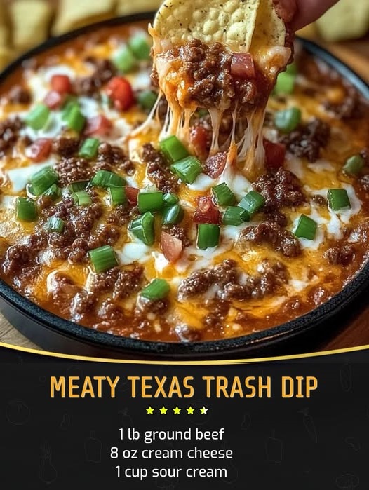 A hot, bubbling dish of Meaty Texas Trash Dip with layers of melted cheese, seasoned ground beef, refried beans, and topped with jalapeños, served with tortilla chips on the side.