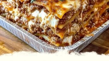 A hearty slice of Million Dollar Lasagna, with layers of rich cheese, creamy ricotta, ground beef, marinara sauce, and perfectly baked golden top, served on a plate.