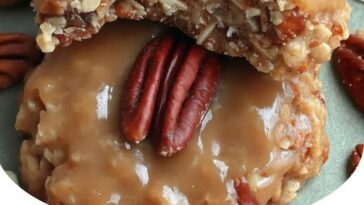 Chewy, golden-brown coconut pecan praline cookies stacked on a plate, with a glossy, caramelized finish and bits of coconut and pecans visible.