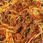 Plate of old-fashioned spaghetti with tomato sauce, garnished with grated Parmesan and fresh basil.