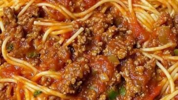 Plate of old-fashioned spaghetti with tomato sauce, garnished with grated Parmesan and fresh basil.