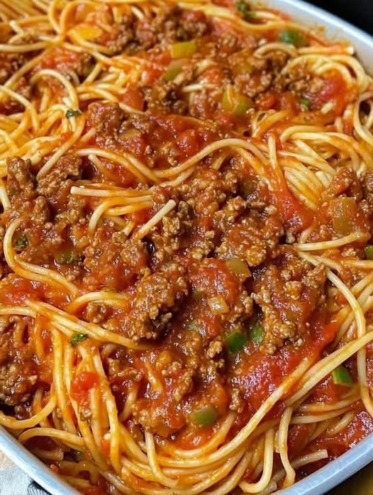 Plate of old-fashioned spaghetti with tomato sauce, garnished with grated Parmesan and fresh basil.