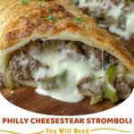 Golden-brown Philly cheesesteak stromboli roll-up, sliced to reveal the cheesy beef filling, on a cutting board.