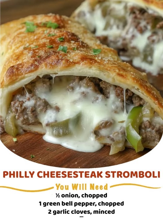 Golden-brown Philly cheesesteak stromboli roll-up, sliced to reveal the cheesy beef filling, on a cutting board.