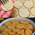 A mix of golden-brown salt crackers and lightly sugared salt cookies arranged on a rustic wooden board.
