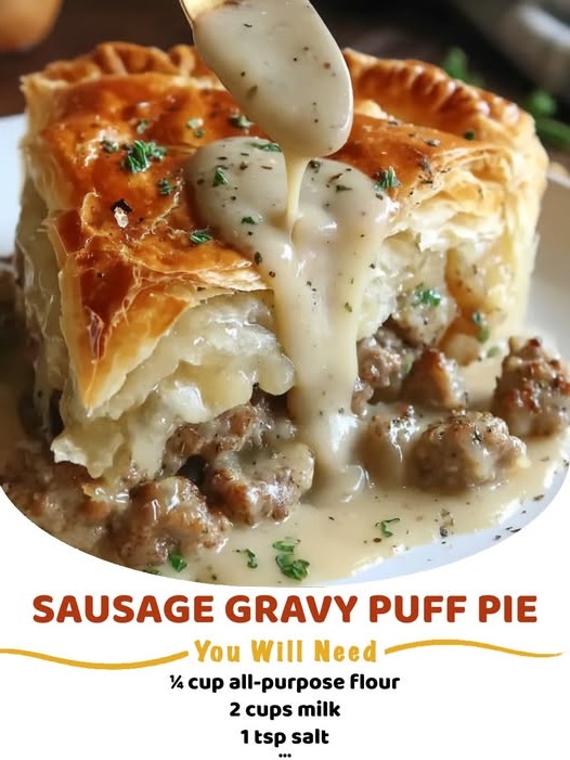 A golden, flaky puff pastry pie filled with creamy sausage gravy, sliced open to show the rich, savory filling.