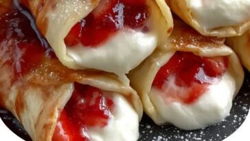 Golden-brown fried chimichangas filled with creamy cheesecake and strawberry filling, dusted with cinnamon sugar and topped with fresh strawberries.