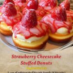 A close-up of strawberry cheesecake stuffed donuts, dusted with powdered sugar and oozing creamy cheesecake filling with chunks of strawberry.