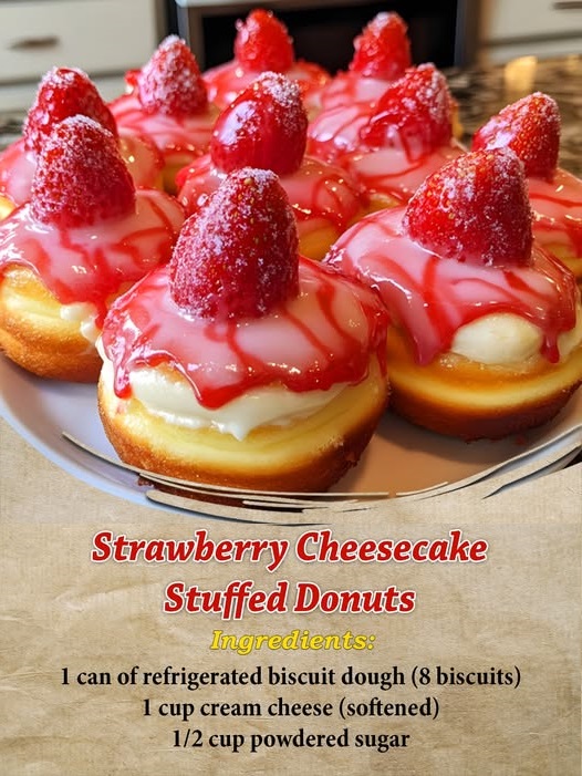 A close-up of strawberry cheesecake stuffed donuts, dusted with powdered sugar and oozing creamy cheesecake filling with chunks of strawberry.