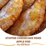 Golden, crispy hand pies stuffed with creamy cheesecake filling and spiced apples, with one pie cut open to reveal the gooey center.