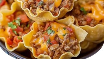 Mini taco ranch bites topped with melted cheese and fresh herbs on a serving platter.