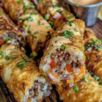 Crispy Voodoo egg rolls sliced open to reveal a spicy, flavorful filling, served with a side of dipping sauce.